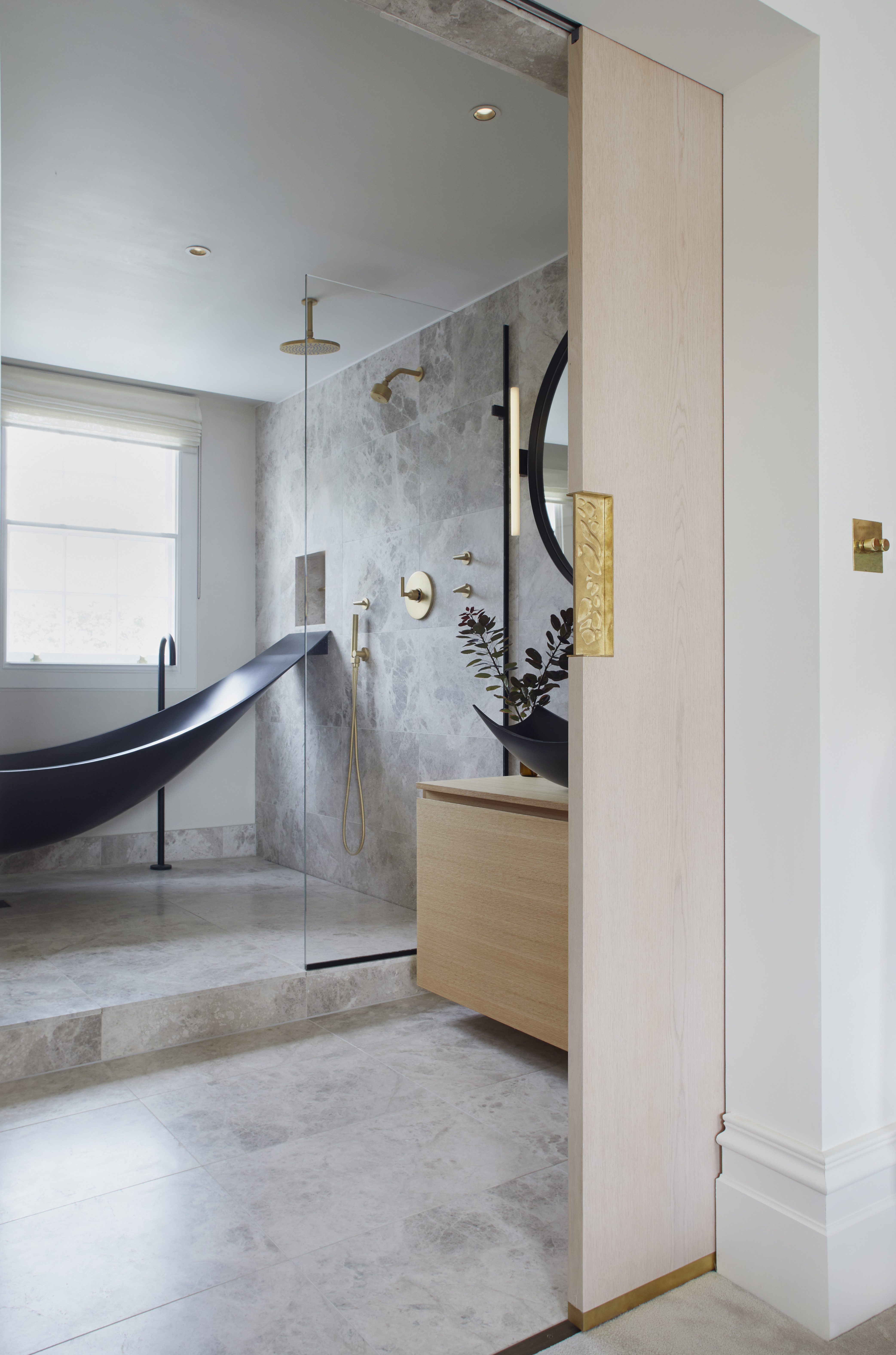 Marble bathroom with sliding door featuring a black hammock bath and black basin