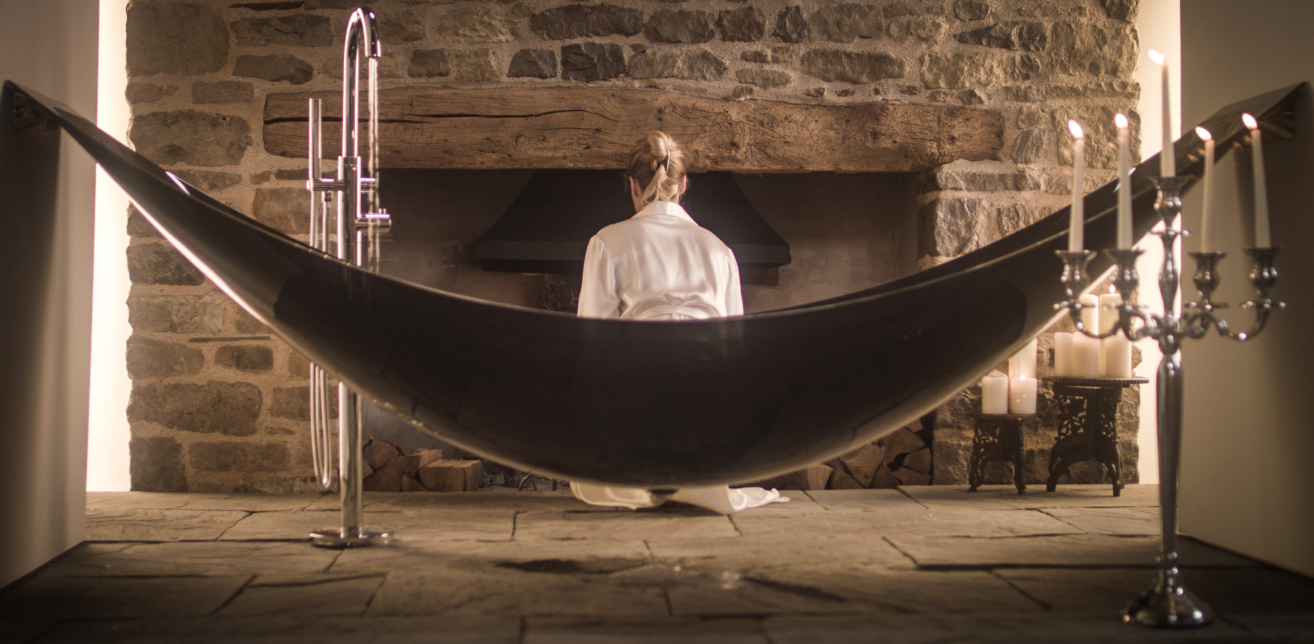 woman lighting fire next to hammock bath