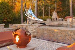 Sculptural pool slide beside lake with fire pit Sculptural pool slide beside lake with fire pit