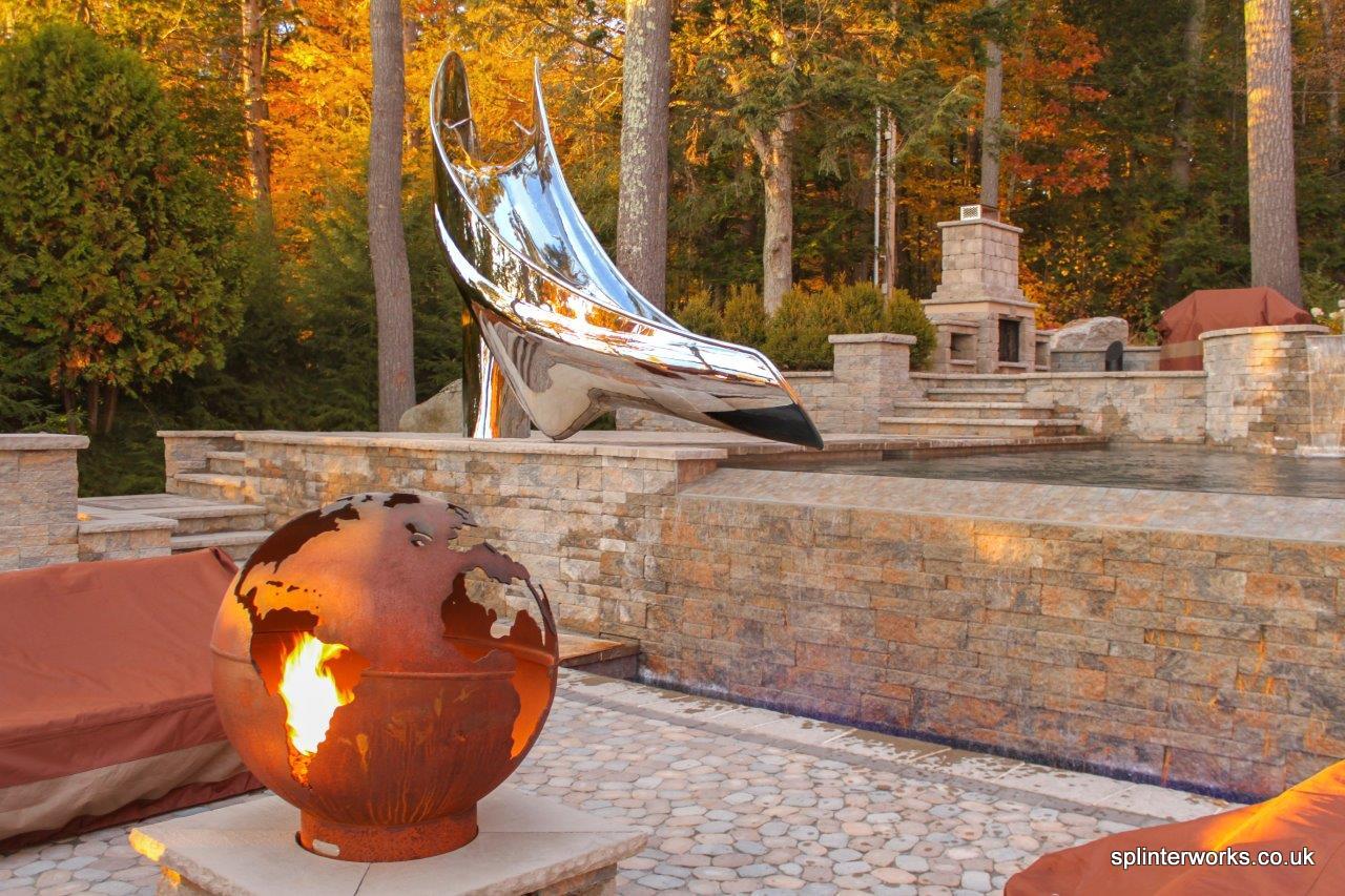 Sculptural pool slide beside lake with fire pit