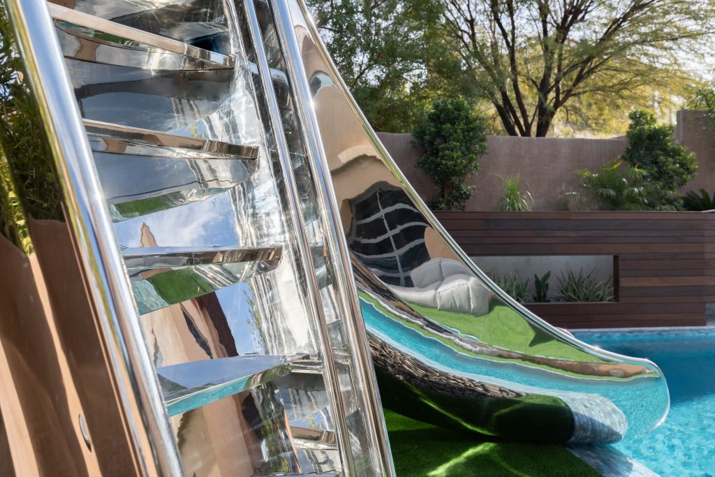 Close up of steps and refelctions of a stainless steel swimming pool slide