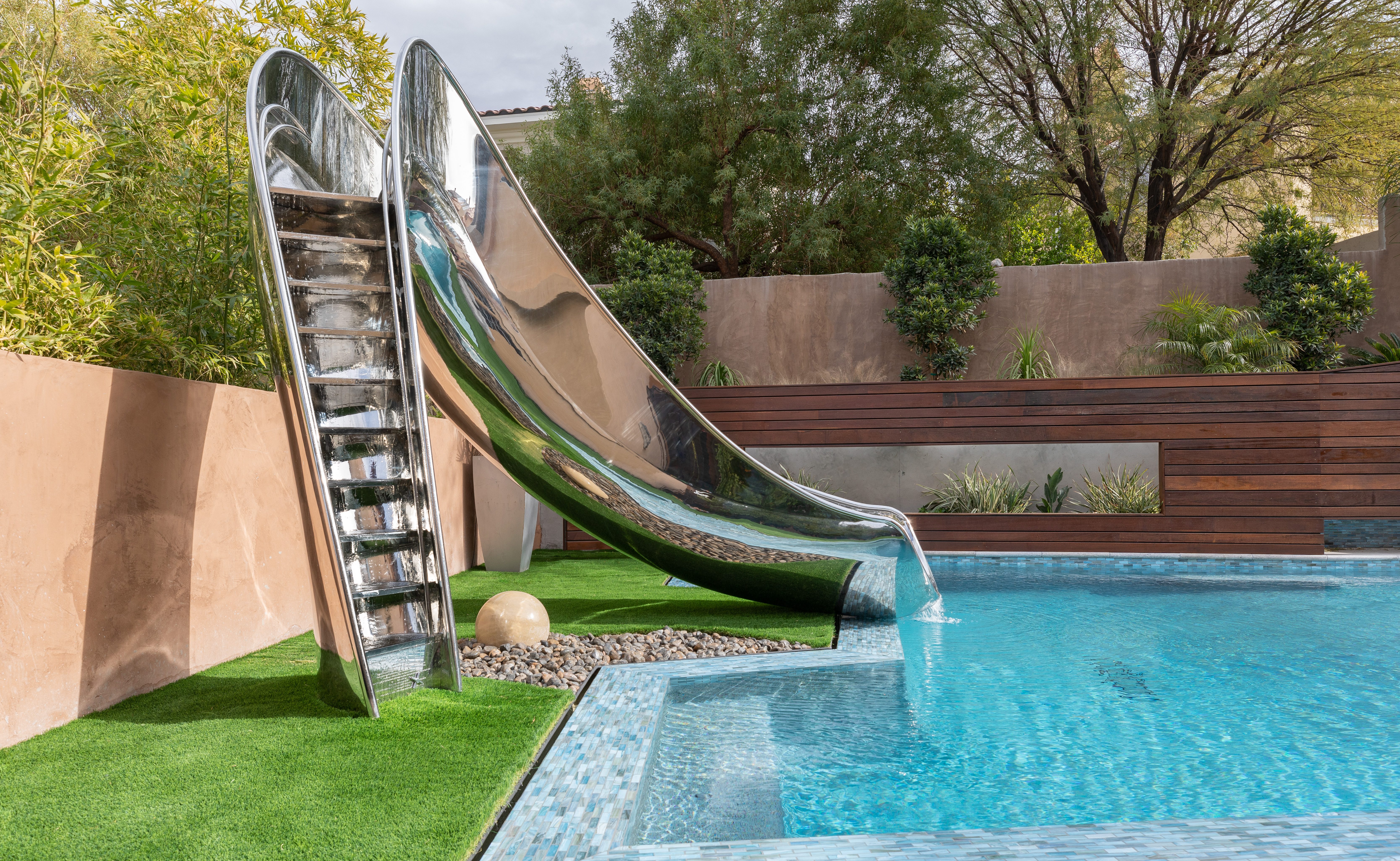 Step view of stainless steel pool slide on astroturf