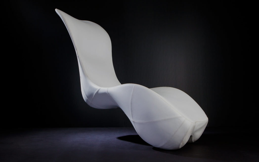 White, sculptural rocking lounge chair on black background White, sculptural rocking lounge chair on black background