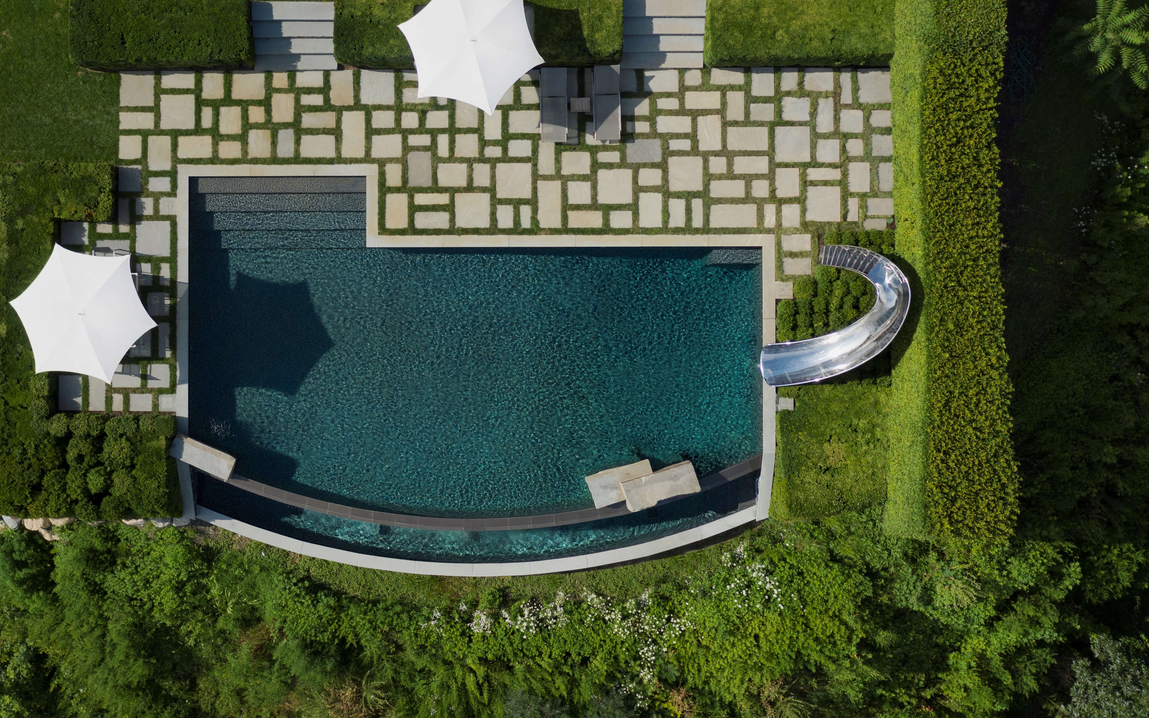 Birds eye view of swimming pool slide with patio.