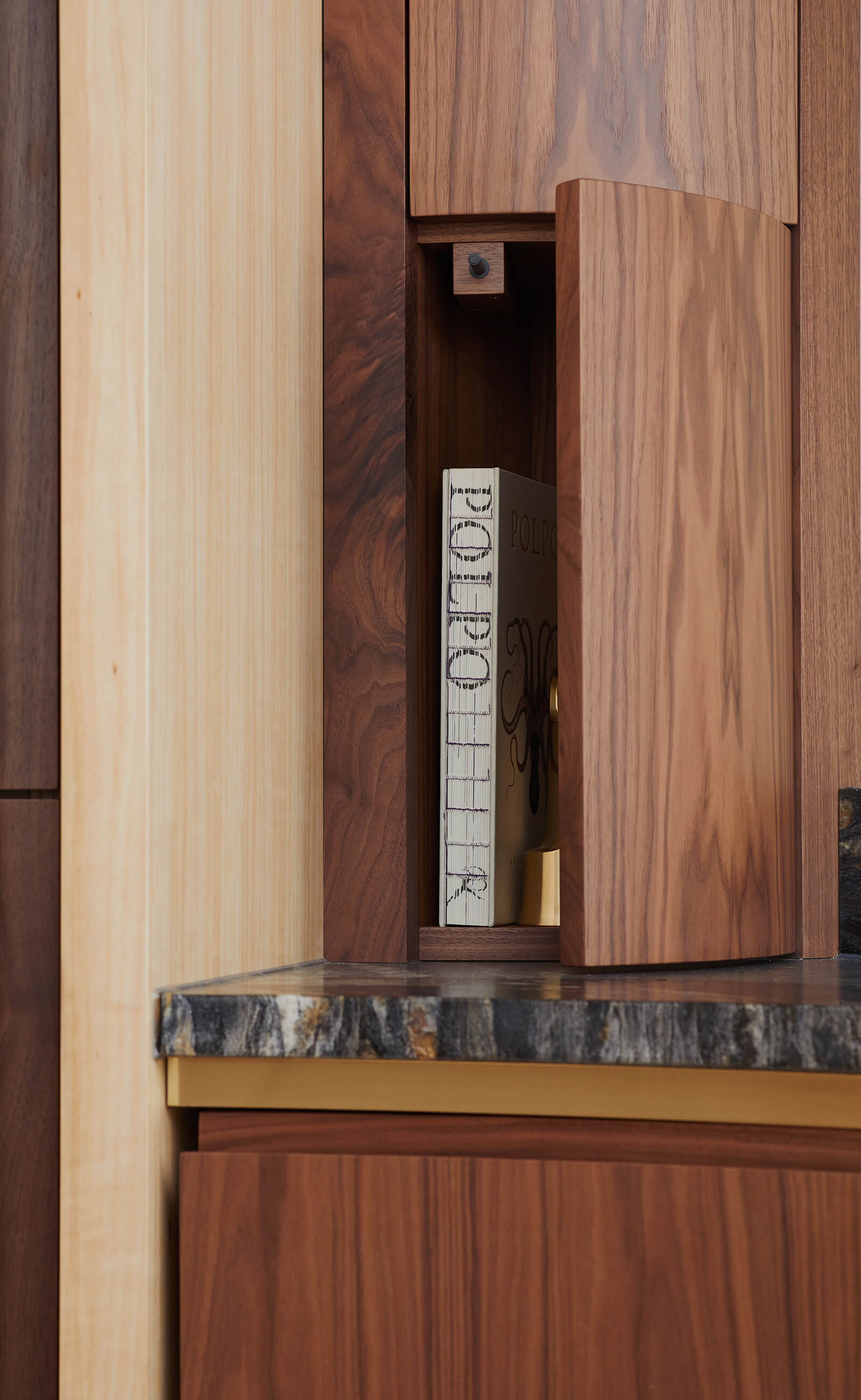 Clever storage in circular kitchen with brass and marble detail.