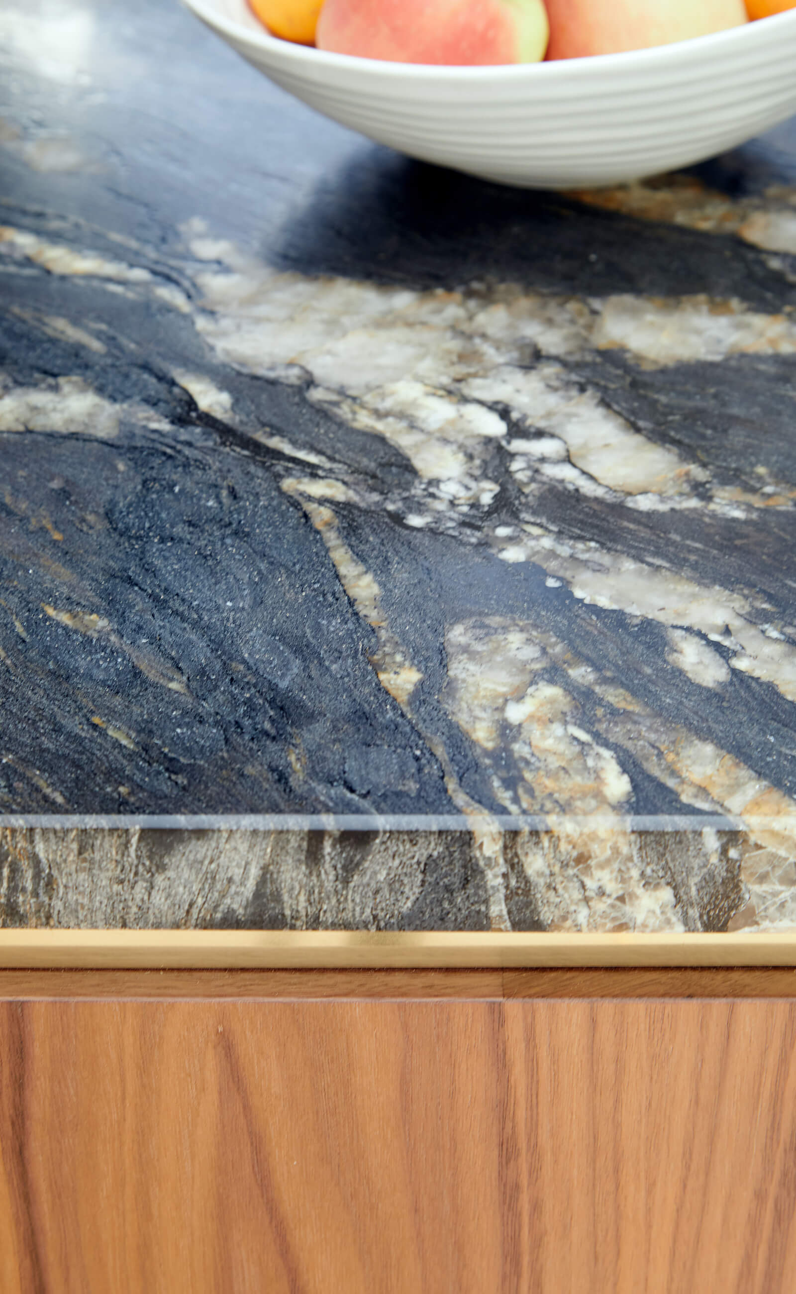 Detail of marble, brass and walnut from contemporary circular kitchen