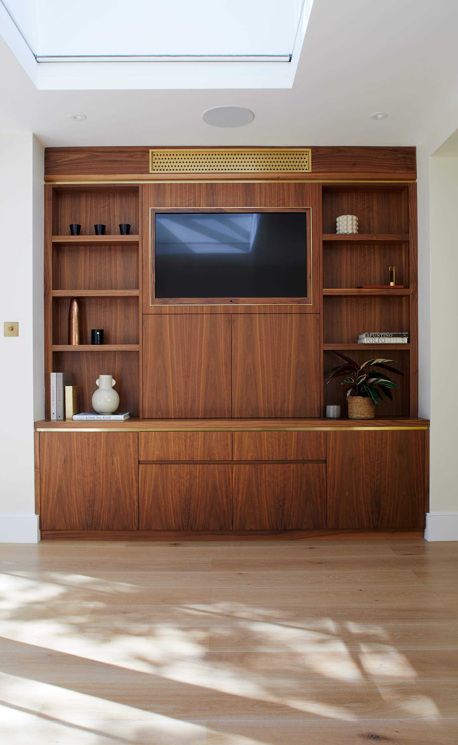 Bespoke walnut cabinetry for TV and air conditioning with brass detail