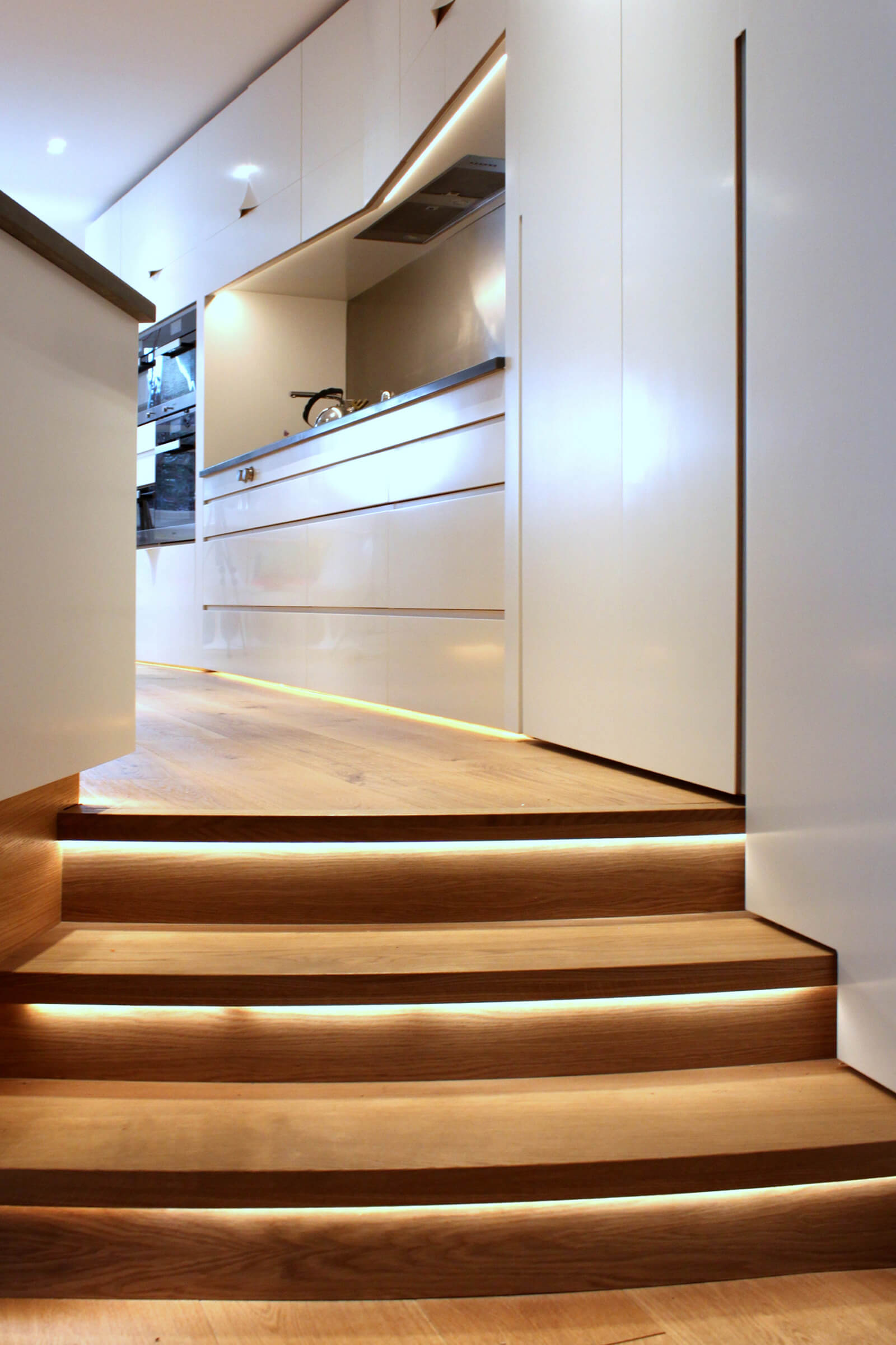 hidden led lighting on steps in white and oak kitchen designed by Splinterworks