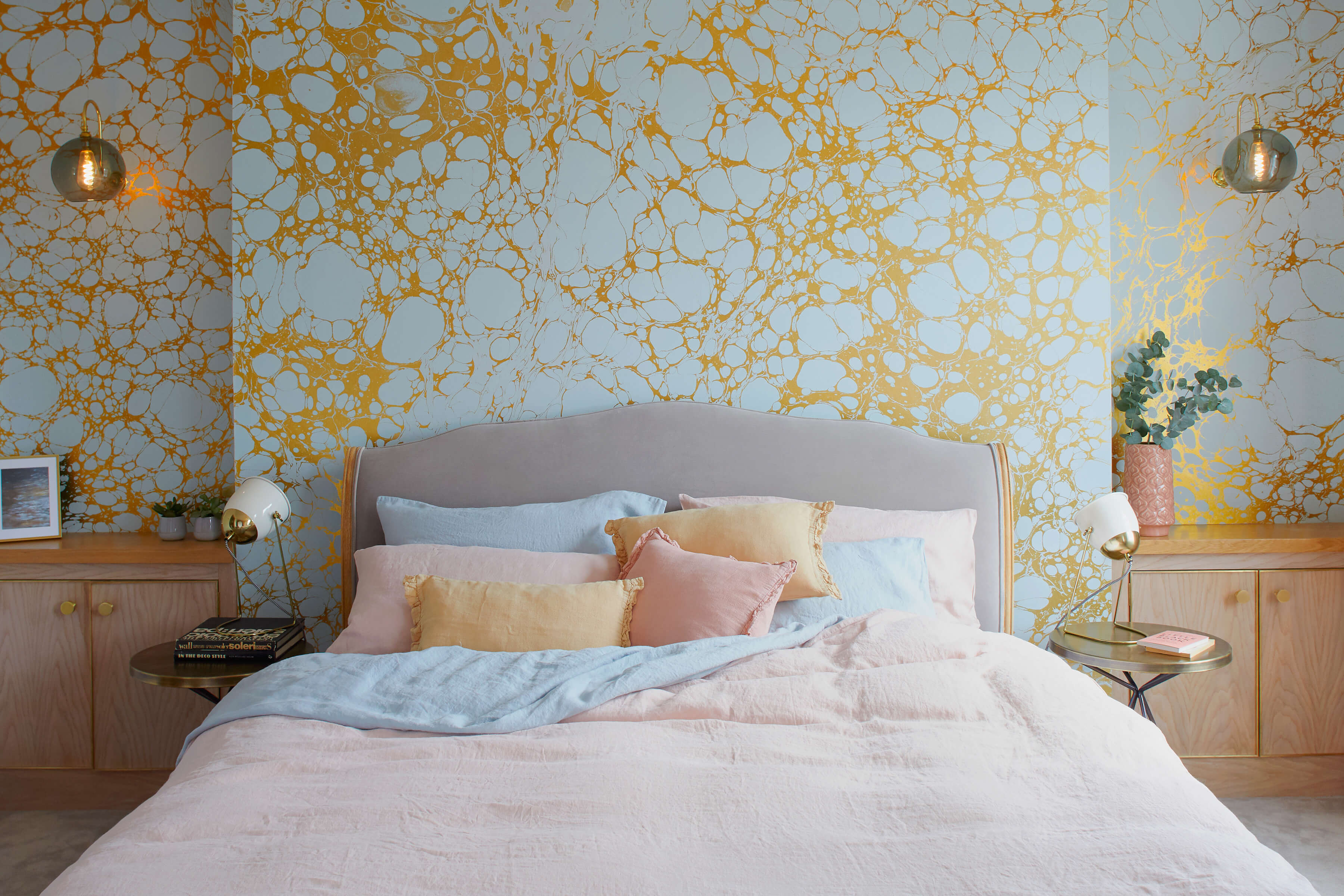 Built in bedside cabinetry bedsides a calm pink bed with gold details on wallpaper