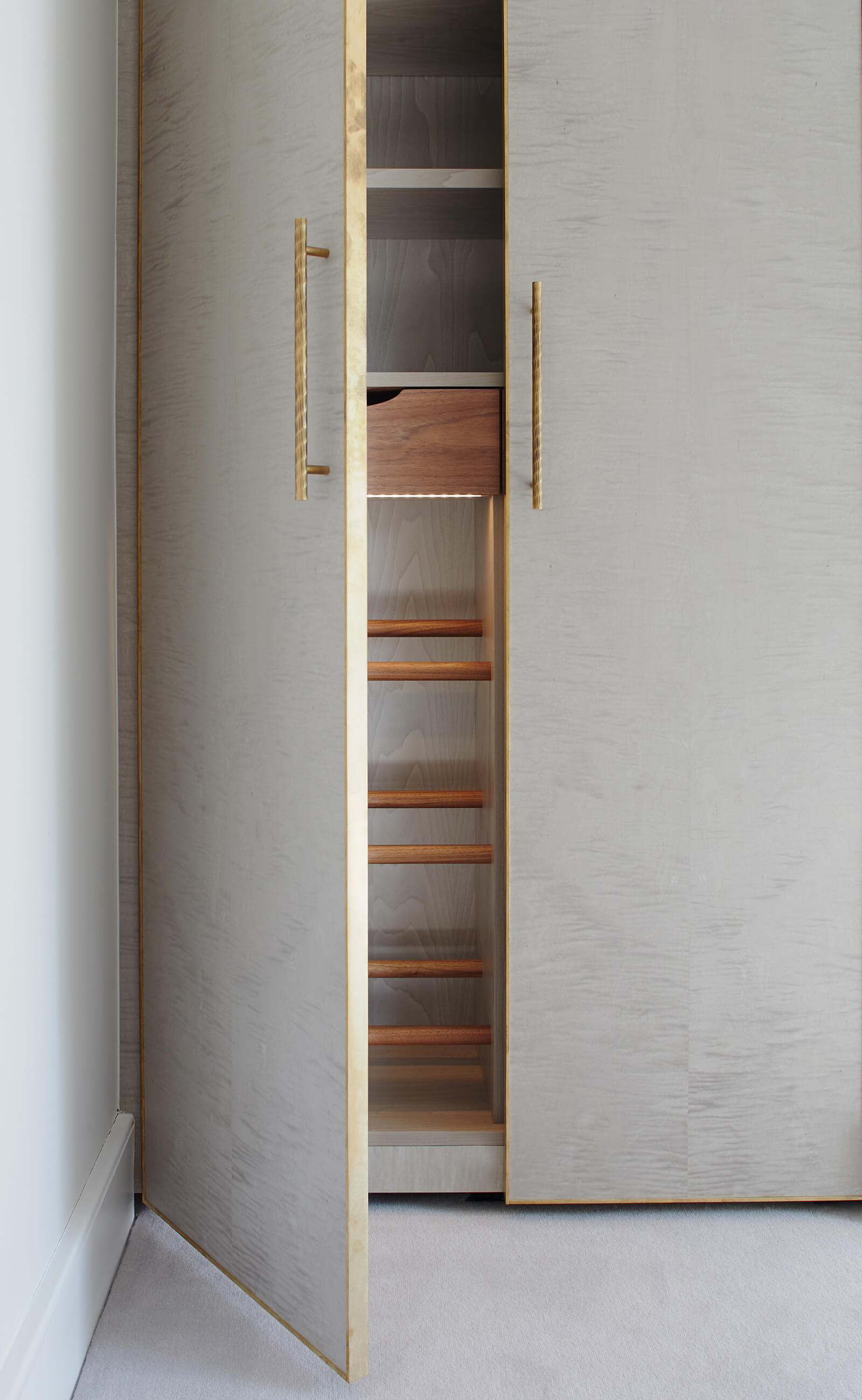 Wardrobe doors with delicate brass edging and custom built shelving in walnut.