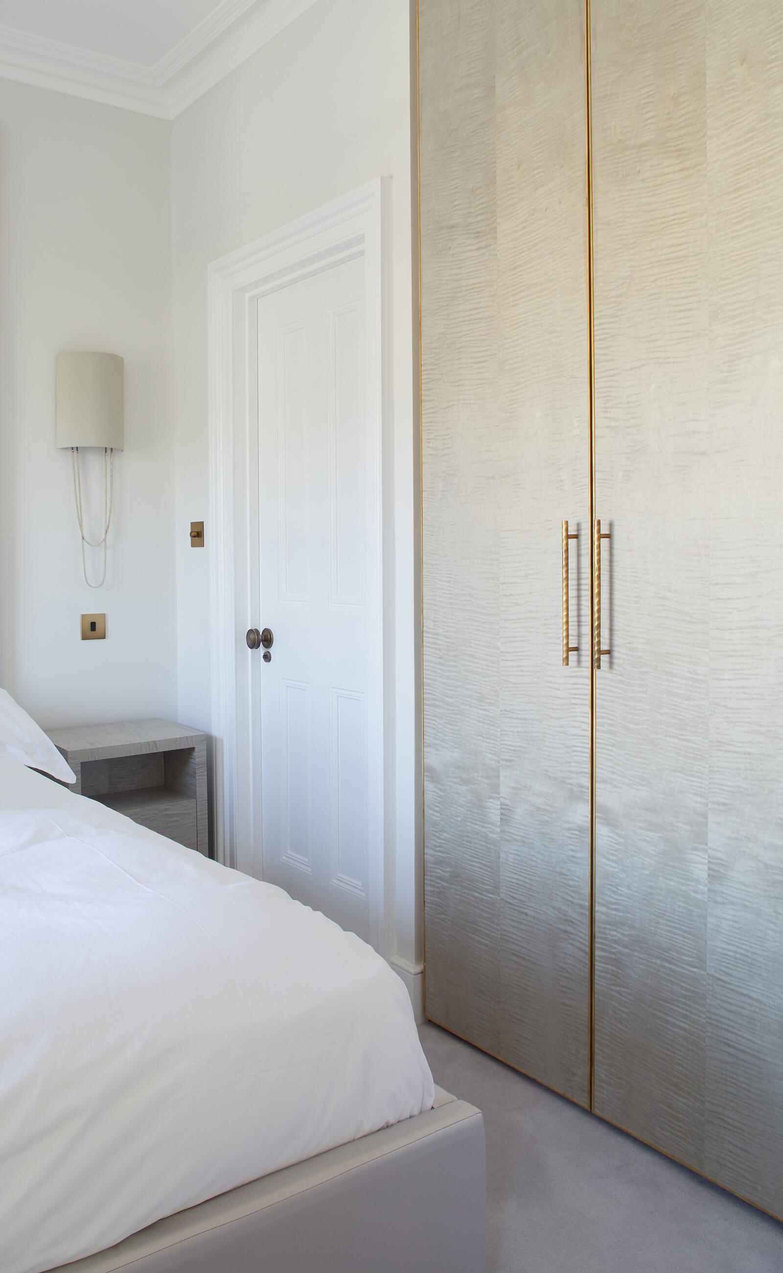 Custom wardrobe cabinetry with brass detail in a serene bedroom