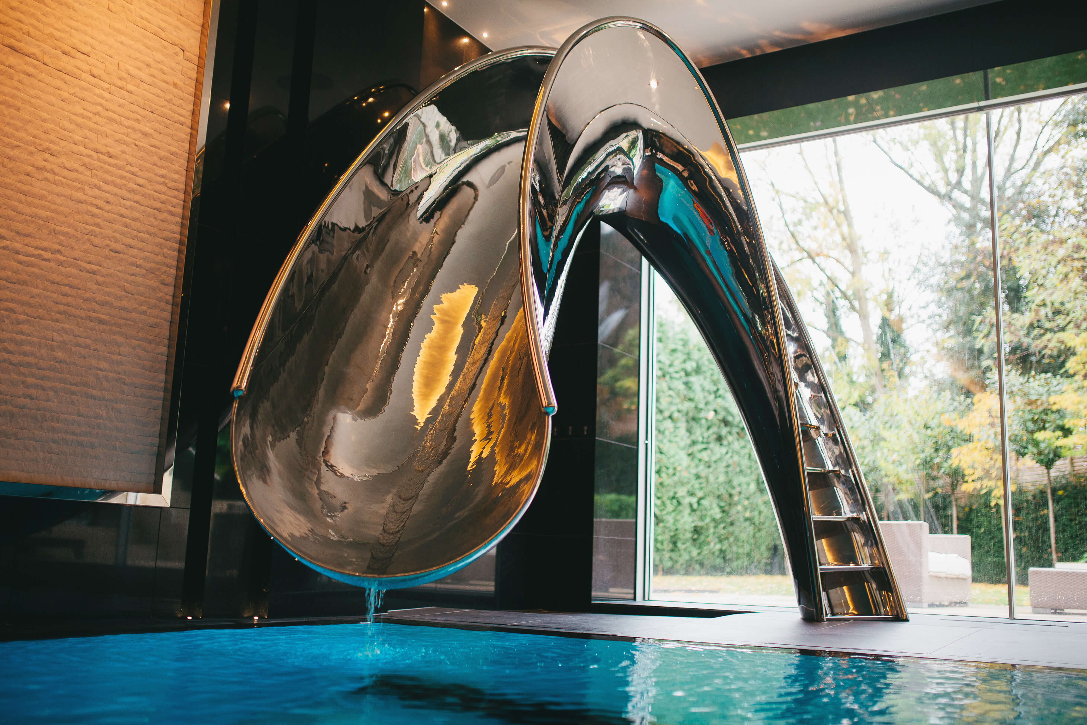 Mirror polished metal water slide for indoor residential swimming pool.