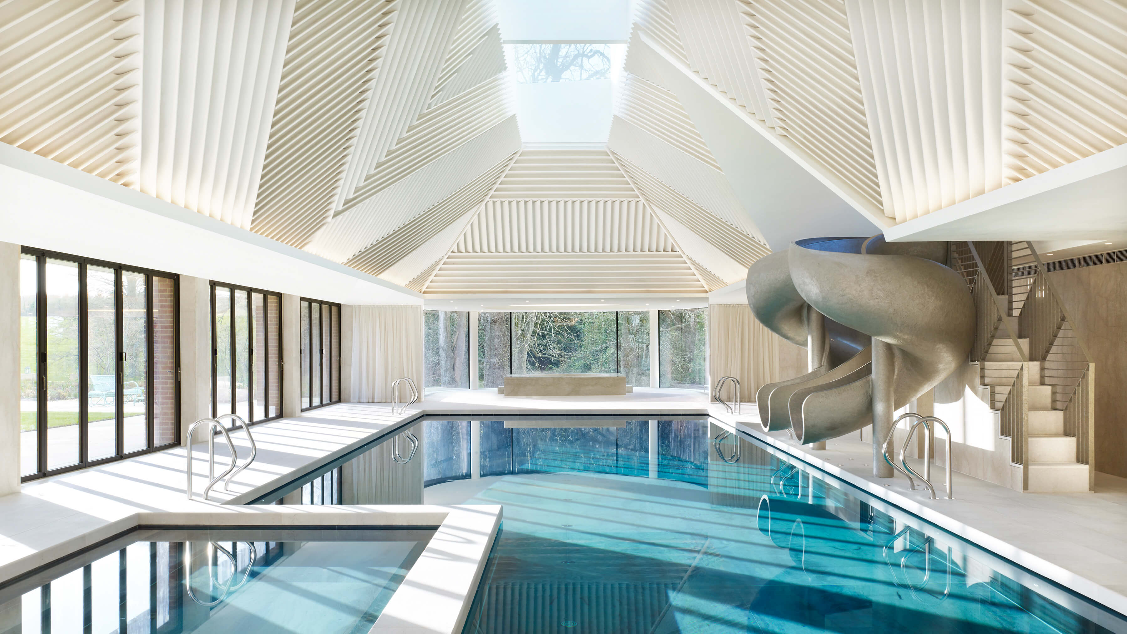 Metallic gold resin pool slide by Splinterworks in spectacular pool pavilion with sky light.