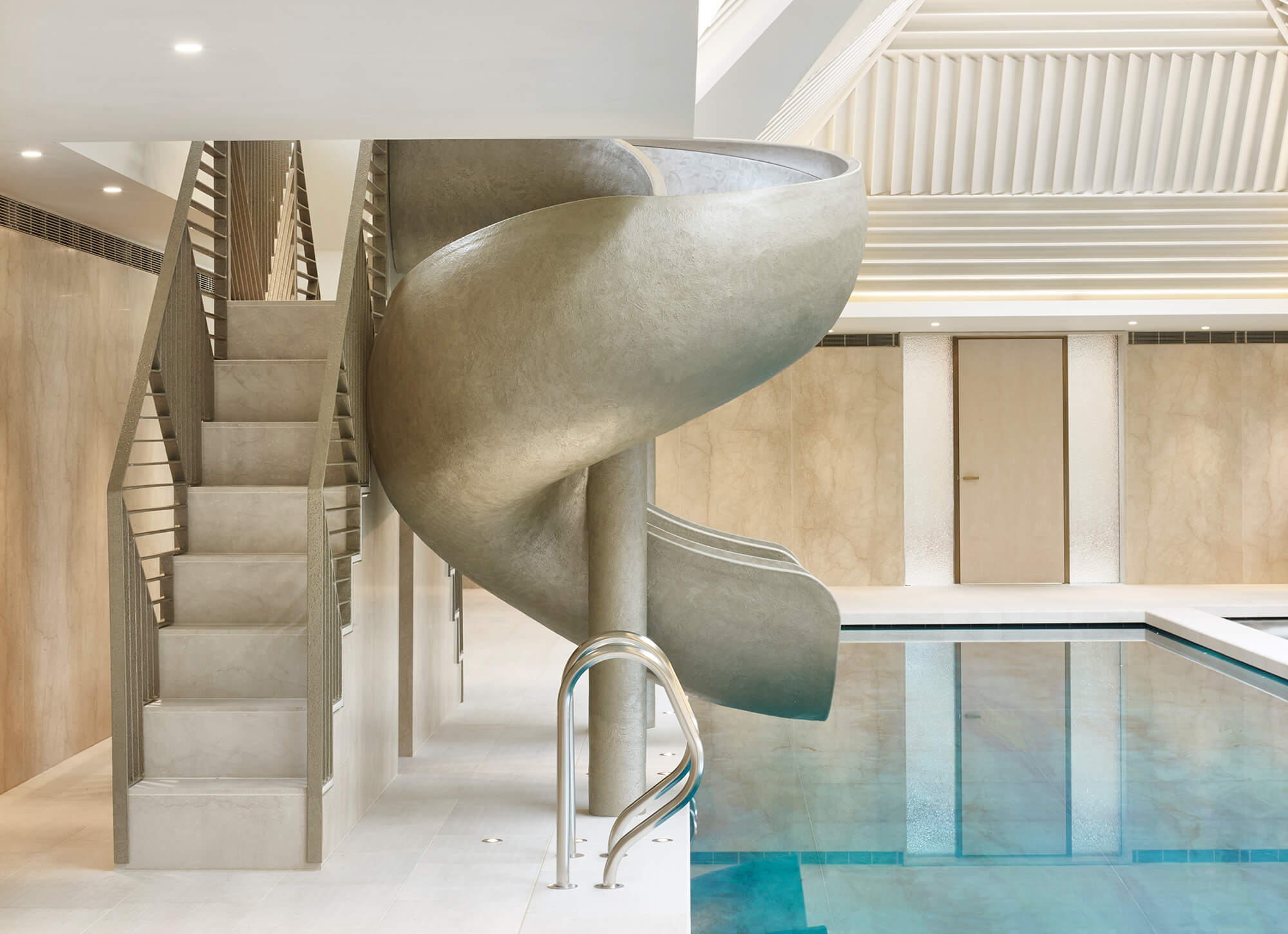 Luxury spiral gold swimming pool slide with steps beside an indoor pool.