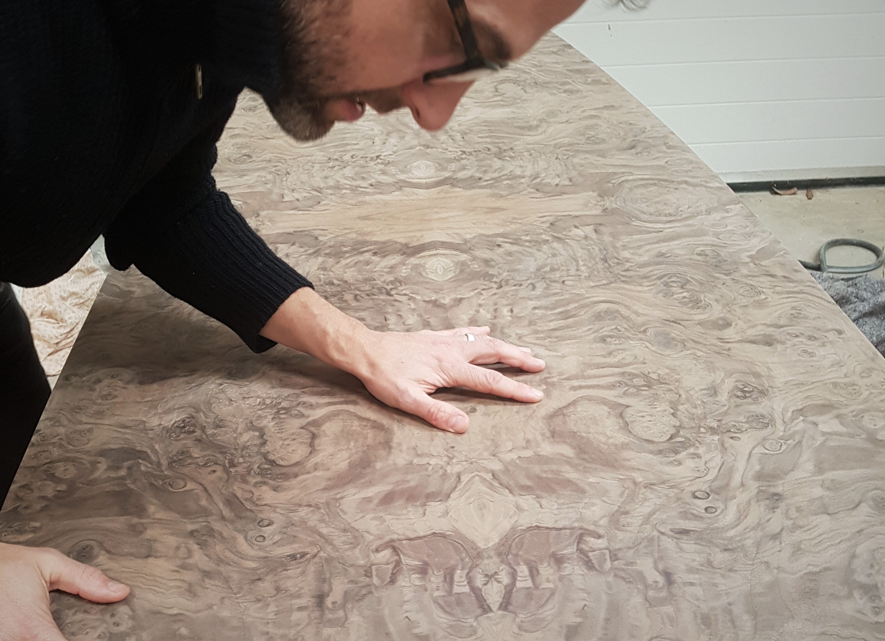 A Splinterworks craftsman examining the unpolished veneer on a bespoke table commission