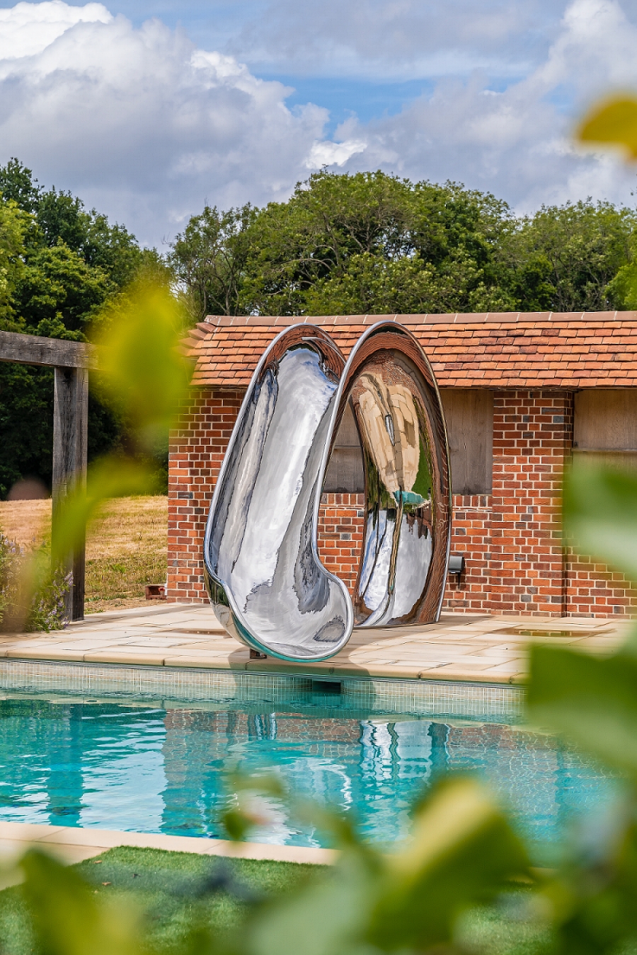 Waha pool slide in front of English country house, taken through foliage