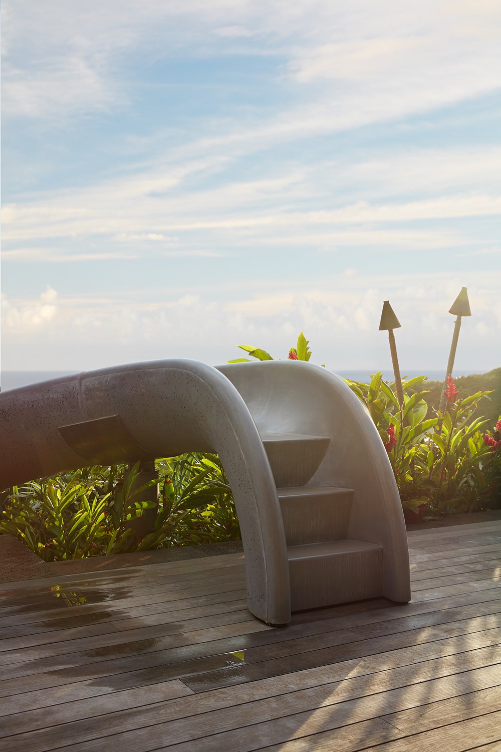 Close up of concrete pool steps in front of tropical plants