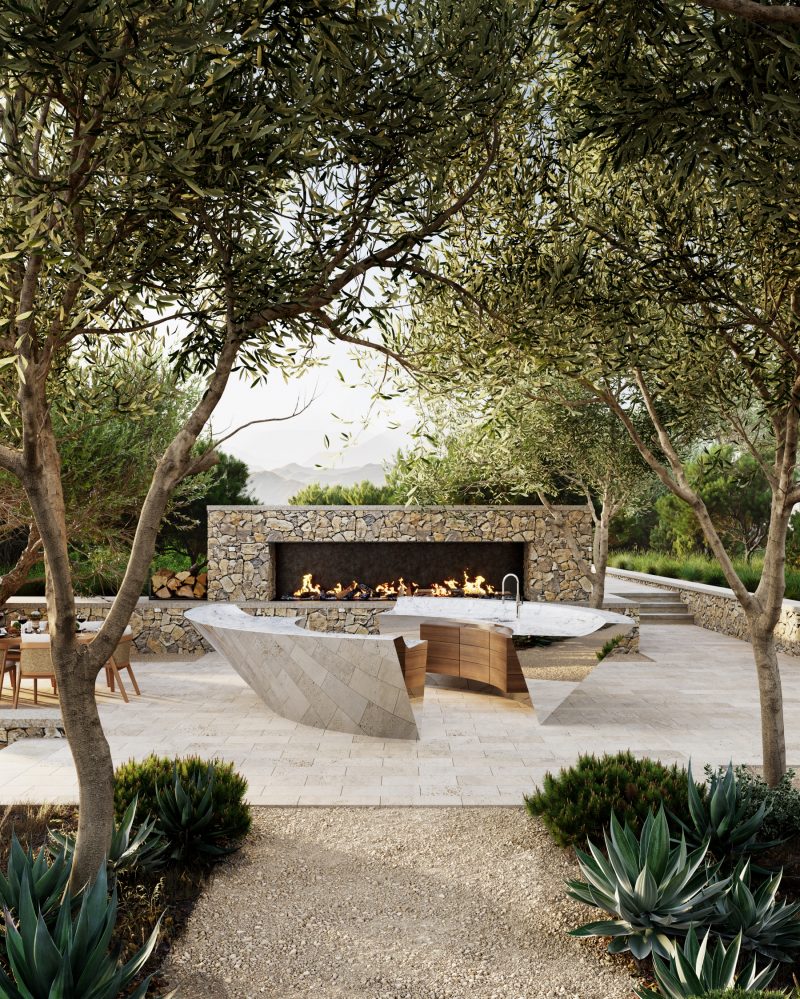 Stainless steel, circular outdoor kitchen surrounded by trees with a fire behind