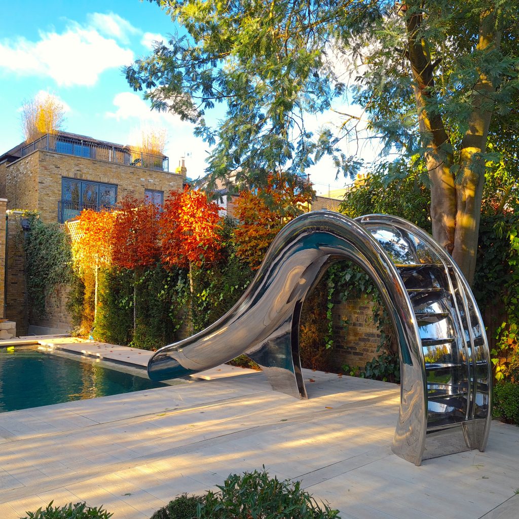 Wave shaped water slide, in London walled garden surrounded by trees