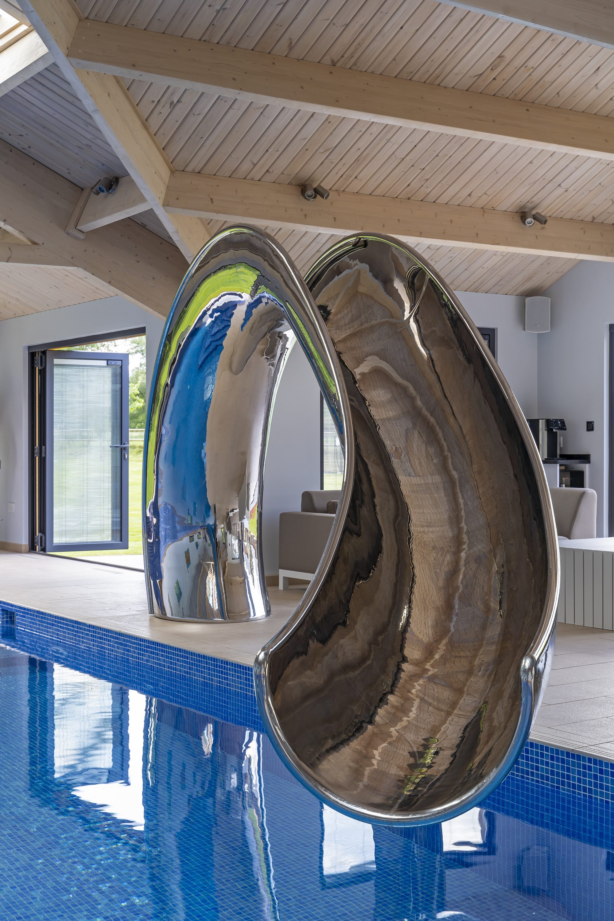 Front view of the pool slide shoot, curving over the pool in indoor pool house
