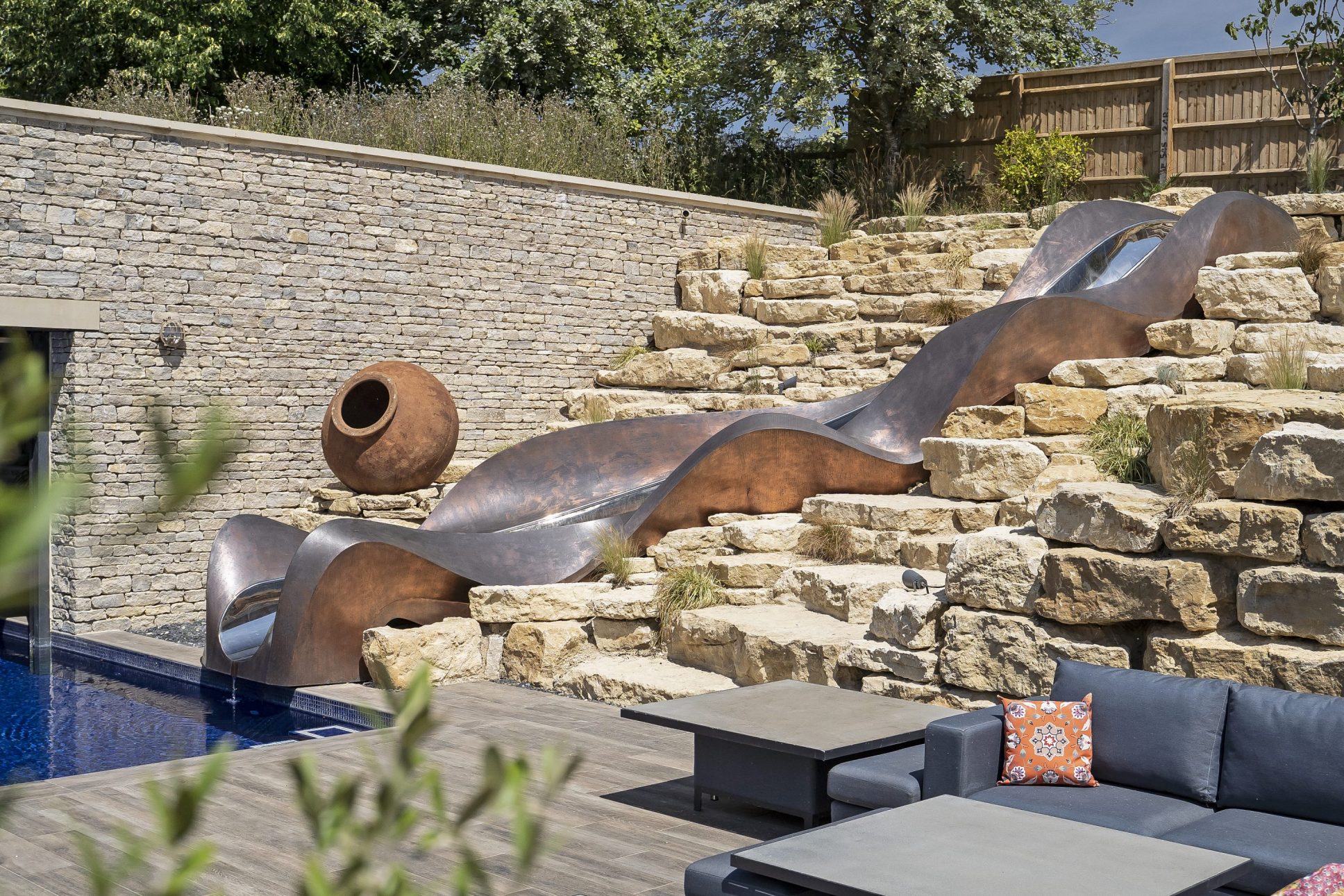 Copper water slide through rockery garden with garden seating to the right