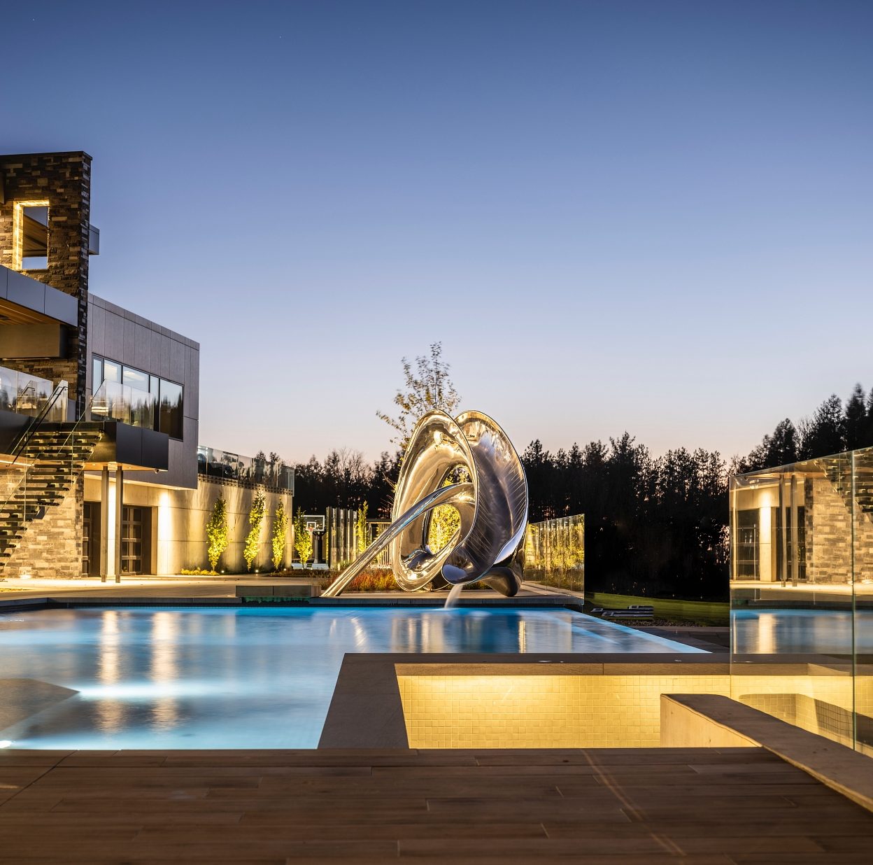 Sculptural Tryst pool slide, taken at night with background lighting on the pool and house